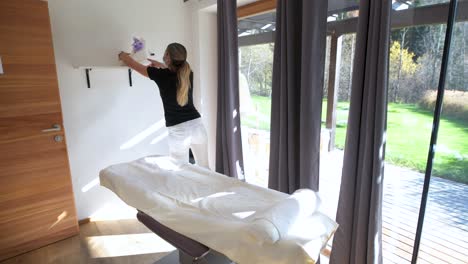 empleado del centro de spa con mascarilla prepara la mesa de masaje