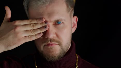 confident stylish bearded man in sensually looking at camera with one eye, posing, facial expression