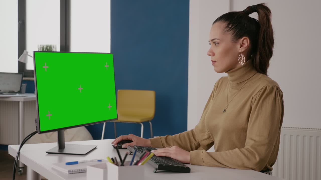 Person looking at green screen on computer display in office