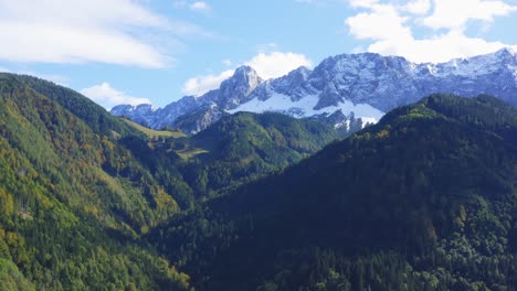 aerial view of forested hill landscape with snow covered mountains in the background