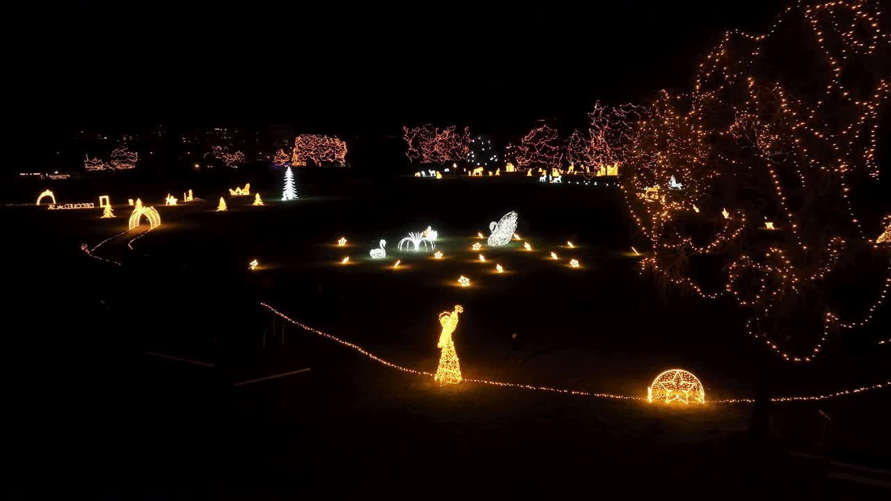 An aerial panning to the left footage of a park transformed into a magical winter wonderland with countless sparkling Christmas lights. LuPa Creative.