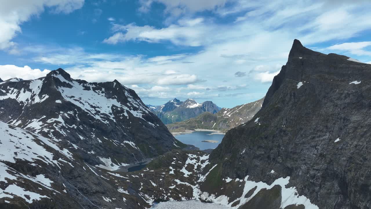 las torres del pico de hornindalsrokken sobre un valle pintoresco con montañas cubiertas de nieve y un lago lejano