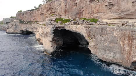 Ondas-De-Agua-Cristalina-Que-Fluyen-En-El-Océano-Y-Chocan-Con-Los-Enormes-Acantilados-Rocosos-De-La-Isla