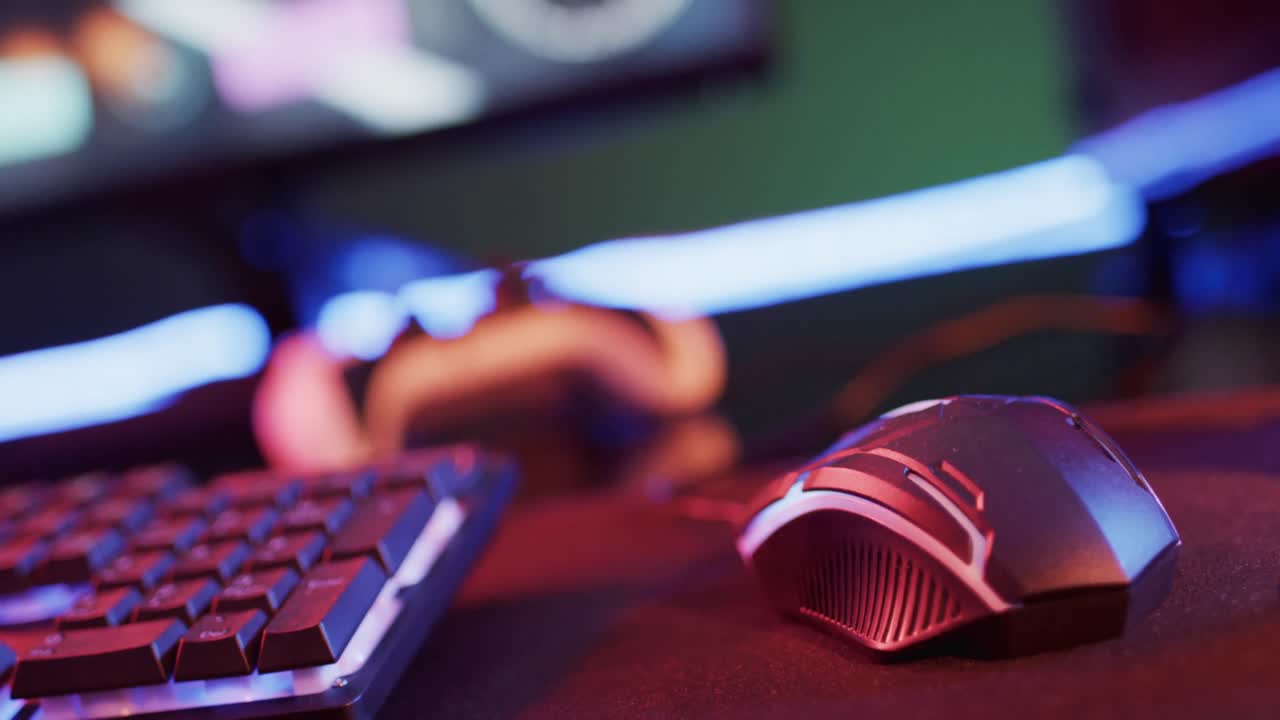 Video of computer and gaming equipment on desk with copy space on neon background