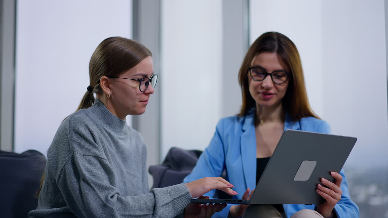 dos mujeres colaborando en una computadora portátil