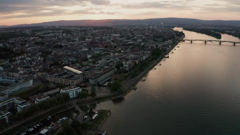 Acercándose-A-La-Iglesia-Dom-De-Mainz-Con-El-Río-Rin-Y-Reflexiones-Sobre-El-Agua-Y-El-Puente-En-El-Fondo-En-Una-Soleada-Noche-De-Verano-Por-Un-Dron