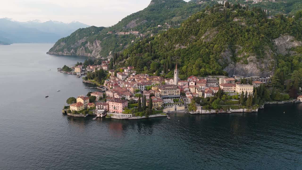 Drone shot of Varenna at dusk, revealing the village and Lake Como in a wide, scenic panorama