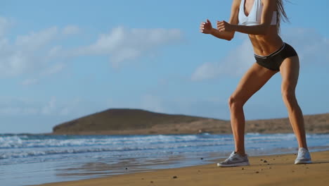 fitness young woman working out core and glutes with bodyweight workout doing squat exercises on beach. sporty girl squatting legs as part of an active and fit life. stedicam shoot