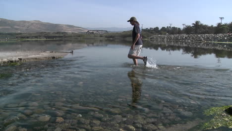 Panning-of-a-man-walking-in-the-water-in-the-Ventura-River-Estuary-at-Surfers-Point-in-Ventura-California