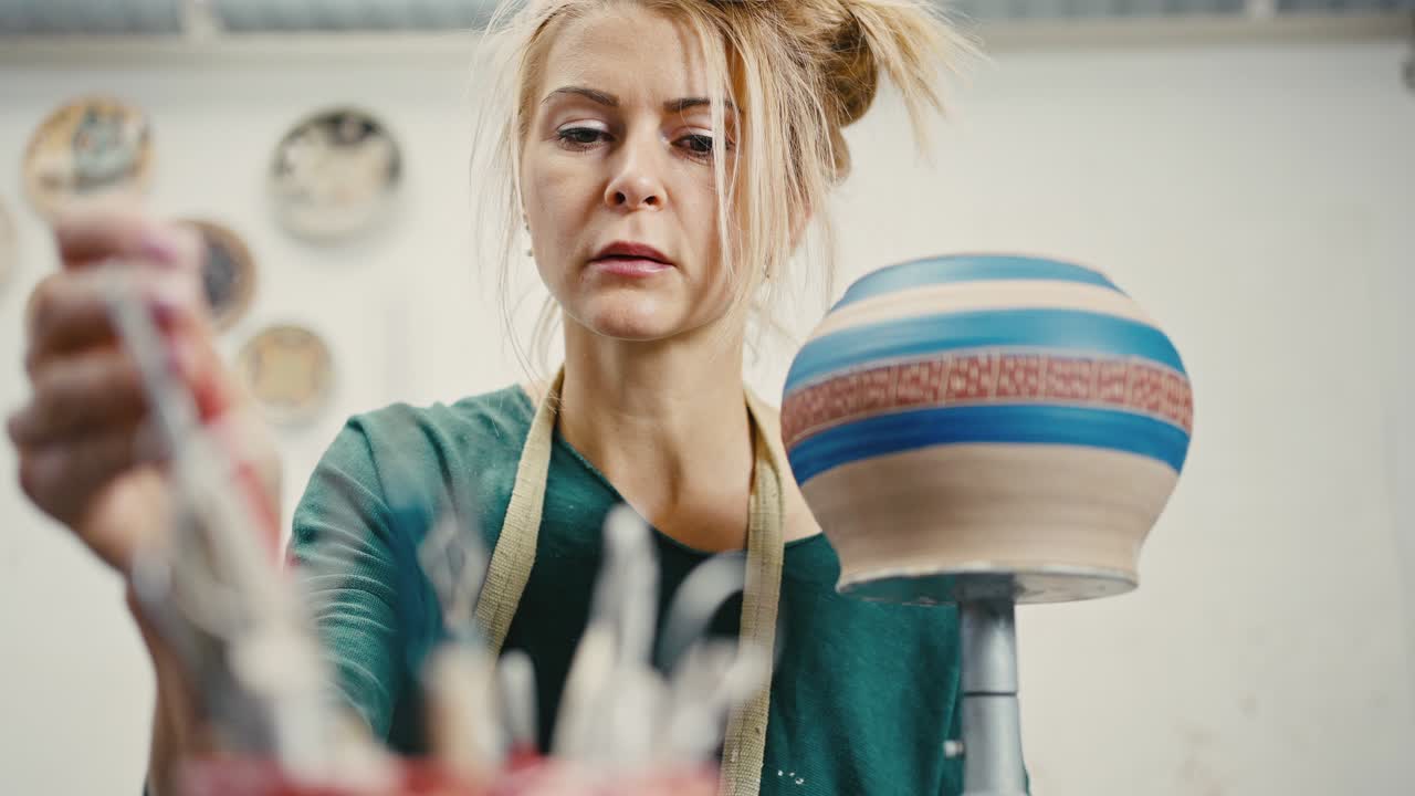 세라 비를 장식하기 위해 작업 도구를 선택하는 여성 도자기의 초상화, 도자기 작업실, 느린 동작