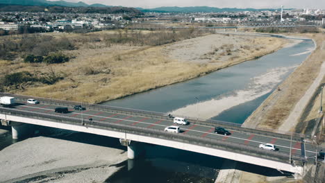 vista aérea del tráfico que cruza el río tama por el puente mutsumi en un día soleado en tokio, japón
