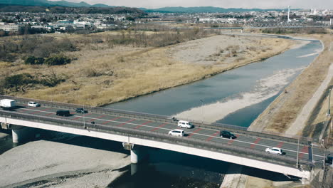 aerial view of traffic crossing tama river by mutsumi bridge on a sunny day in tokyo, japan