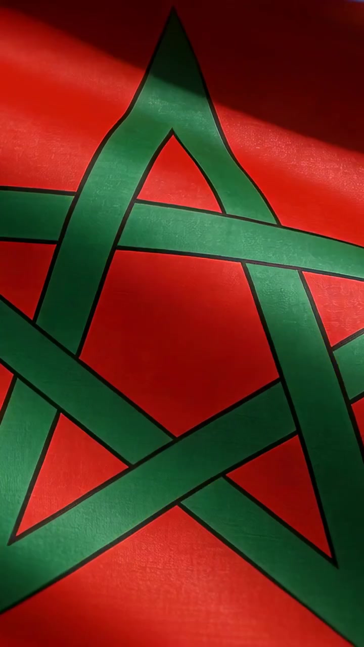 Video verticale: Bandiera rossa che sventola con un pentagramma verde nella brezza, la telecamera si alza rivelando il cielo.