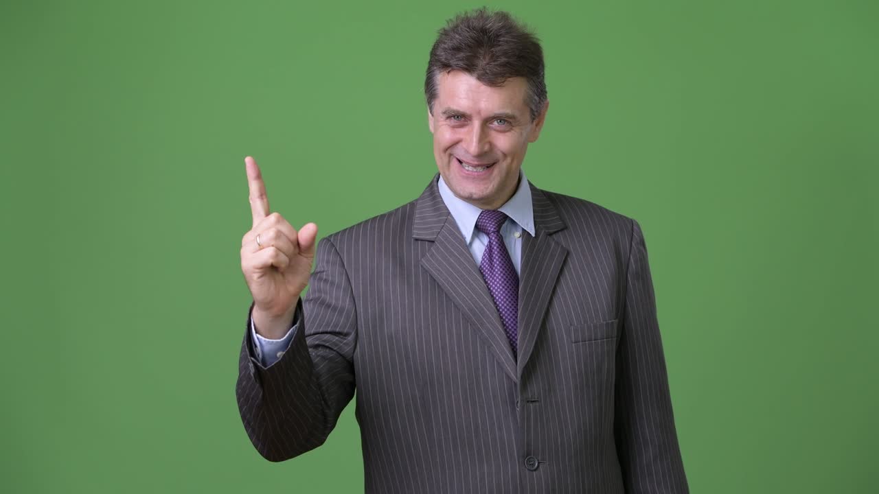 hombre de negocios maduro y guapo contra un fondo verde