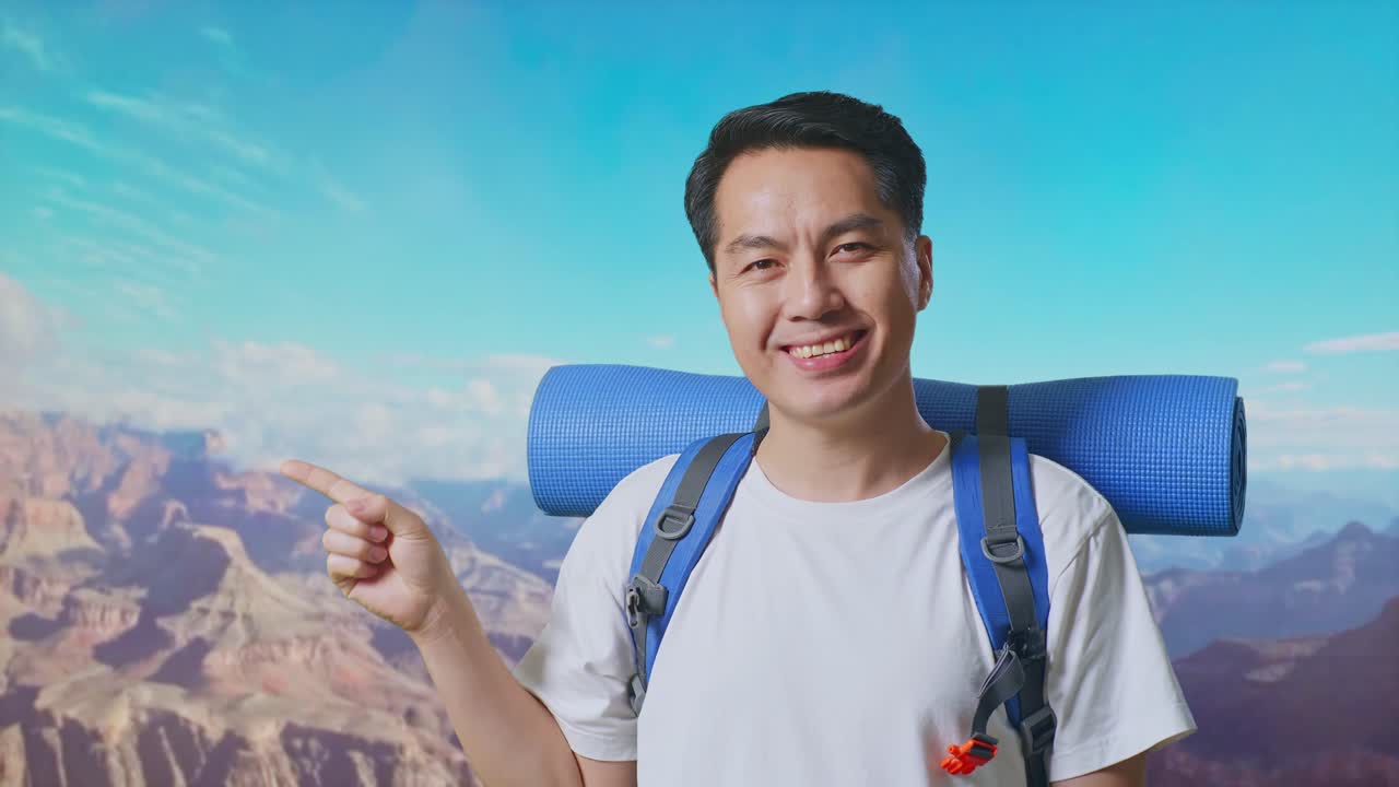 Close Up Of Asian Male Hiker With Mountaineering Backpack Smiling And Pointing To Side While Traveling At The Top Of Mountain