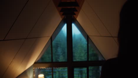 silhouette of a girl who looks out the window at the green forest in the mountains. nice view from the window