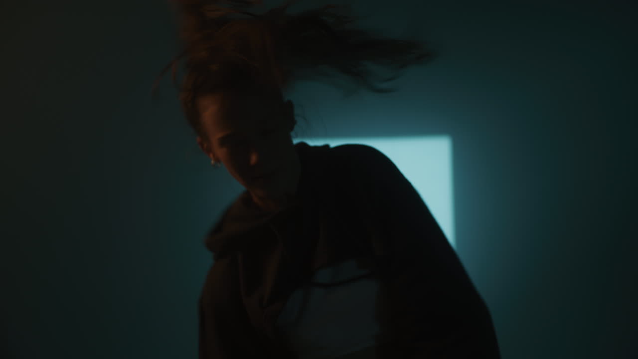 A Woman Dancing in a Dark Studio