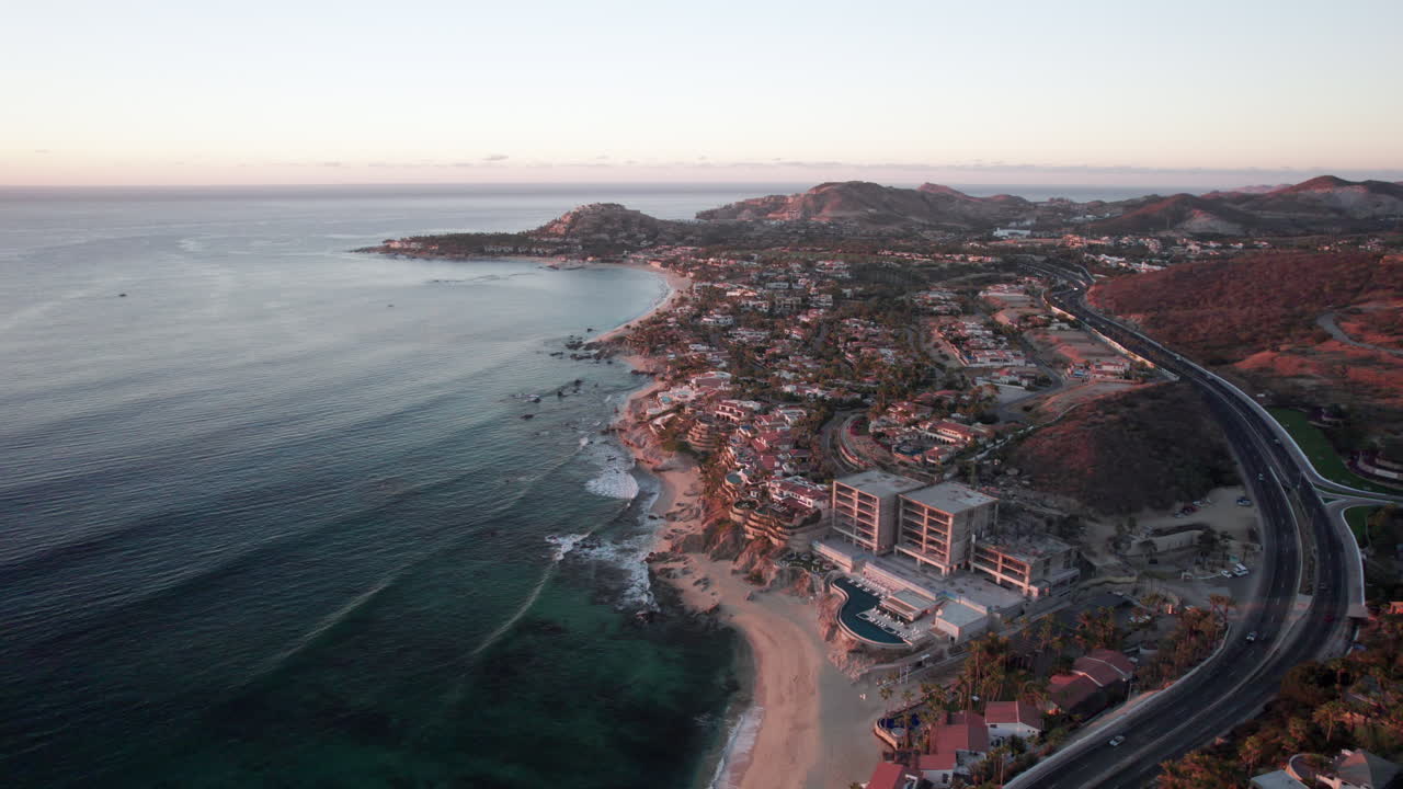 pan órbita drone tiro de la costa tropical de los cabos méxico y el océano tranquilo con resorts y carretera costera