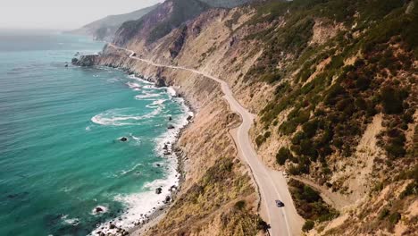 Aerial-tracking-shot-of-a-car-driving-along-a-Pacific-highway-coast-in-California-in-USA