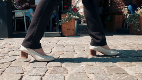 people walk on a crowded sidewalk, close up view of the sidewalk and legs to knee height, slow motion on shoes and footsteps