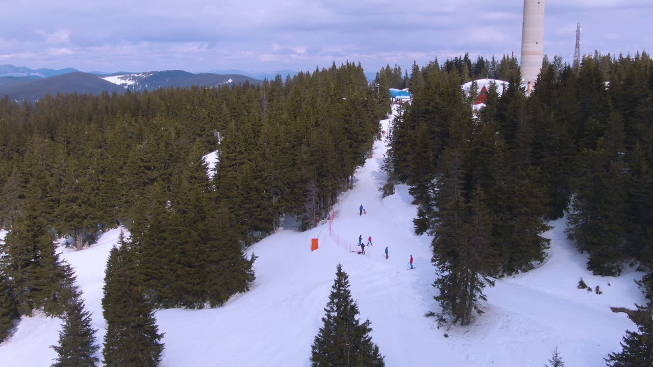 Zooming drone shot of people skiing near TV tower