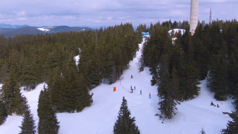 zooming drone shot of people skiing near tv tower