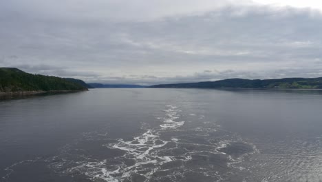 View-of-mountains-from-the-stern-of-a-ship-cruising-along-Saguenay-Fjord-outside-of-La-Baie,-QC,-Canada