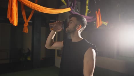 tough man drinking water from the bottle in the dark gym