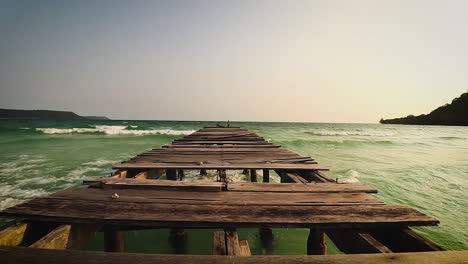 Ein-Zerbrochener-Holzsteg-Mit-Blick-Auf-Das-Offene-Meer-Am-Strand-Von-Soksan-Auf-Der-Insel-Koh-Rong-In-Kambodscha,-Der-Ein-Beliebtes-Touristenziel-Im-Sommer-Ist