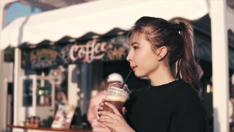 young woman enjoying iced coffee at outdoor cafe