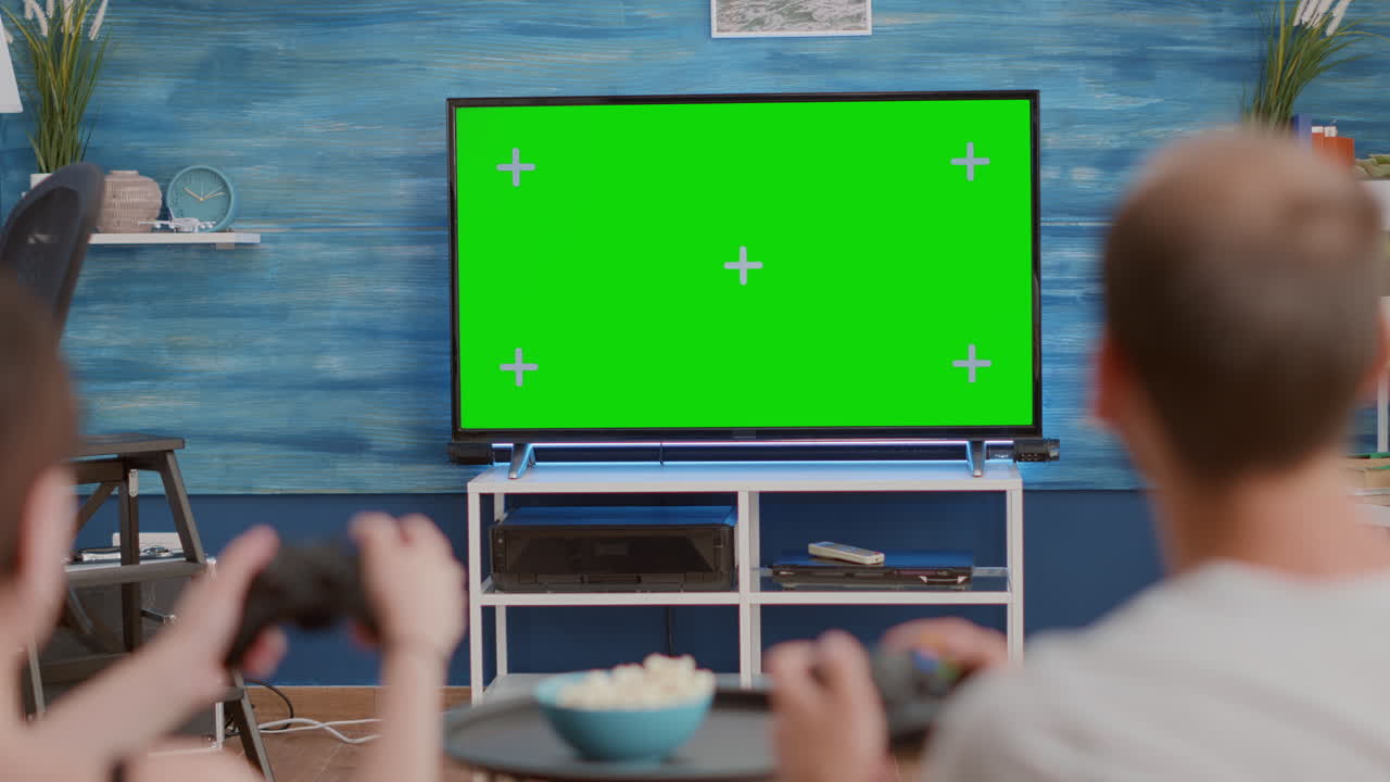 Closeup of couple holding controllers playing actin console games on green screen tv sitting on couch