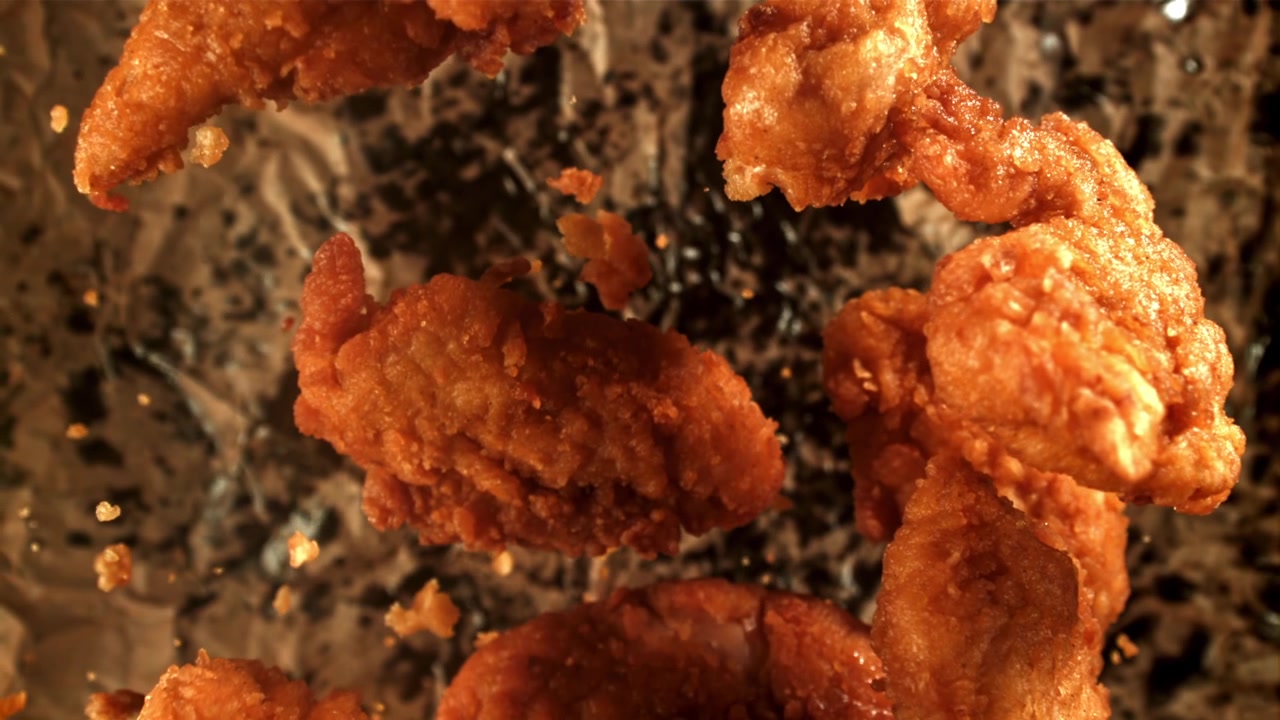 Bocconcini di pollo fritto croccanti che fluttuano al rallentatore.