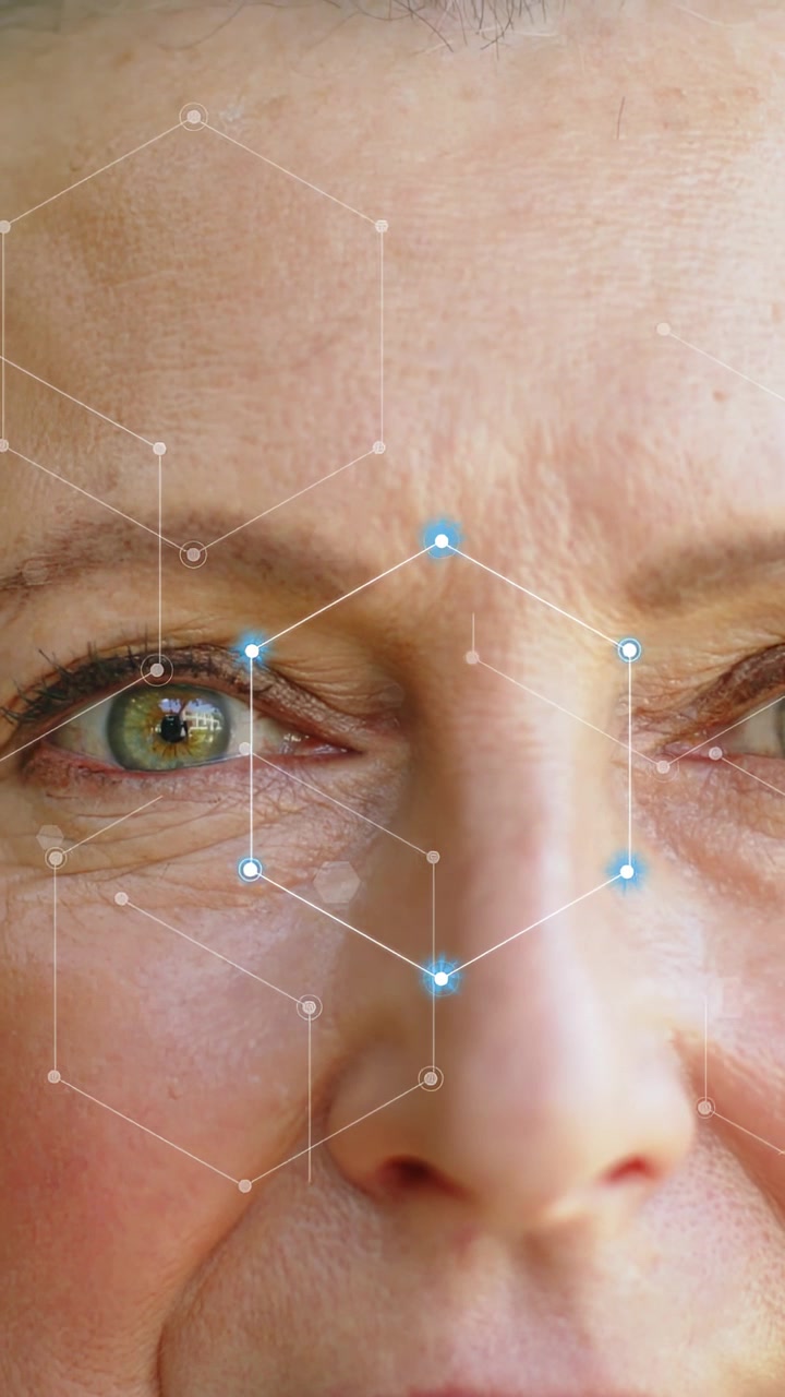 Vertikales Video: Reife Frau öffnet die Augen, während sich ein blauer Knoten auf der Stirn zu sechseckigen Knoten für Gesichts-Mapping formt.
