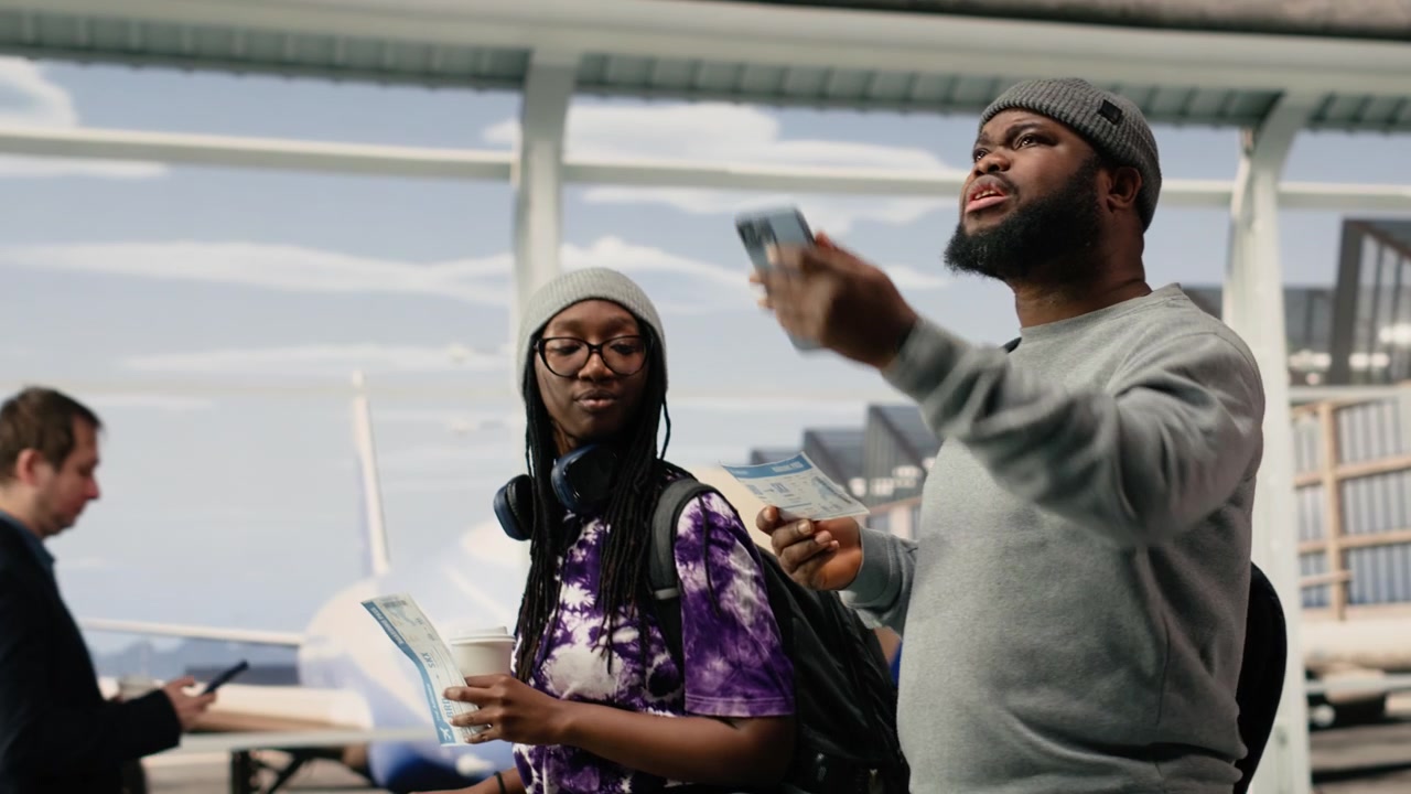 Coppia nel terminal dell'aeroporto che guarda lo schermo dello smartphone e la carta d'imbarco