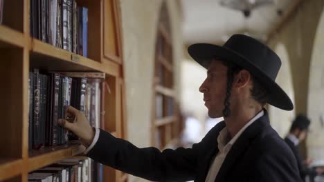 jewish man selecting a book from a bookshelf in a library