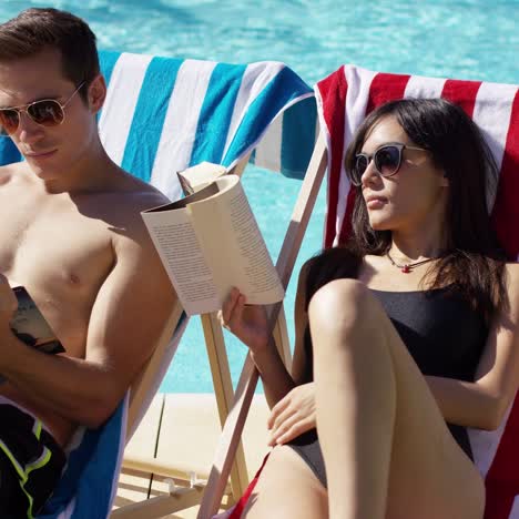 Young-couple-reading-books-at-the-swimming-pool