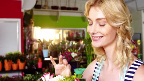 beautiful female florist checking rose in flower shop