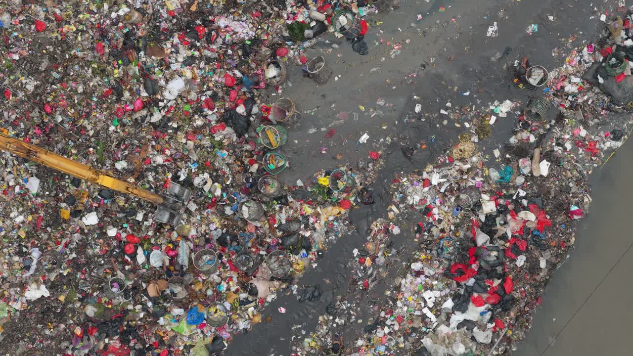 Bulldozer che sposta i rifiuti in una vasta discarica di Jakarta