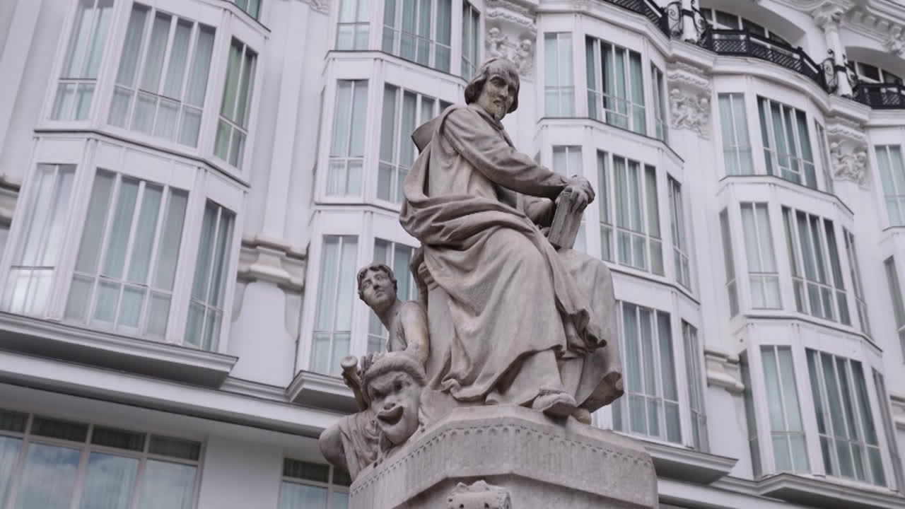 Beautiful slow motion zoom in shot of a famous statue of old artists in the city of Madrid during the day.