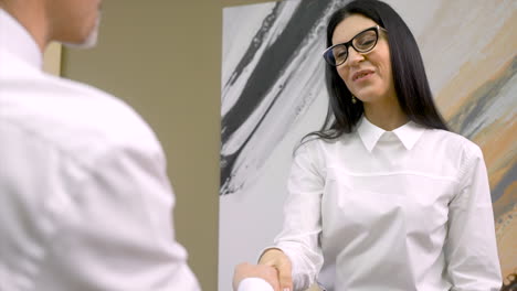 close up of a happy female boss receiving document from an employee and shaking hands with him