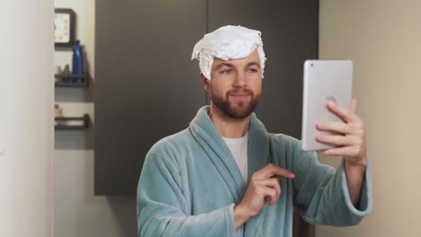 un hombre alegre con un peinado de espuma se toma un selfie en una tableta
