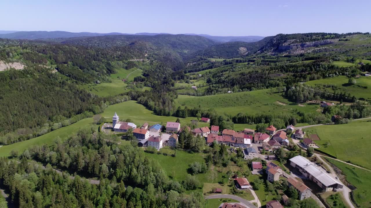 sobrevuelo aéreo pueblo francés les bouchoux durante el día soleado y el paisaje verde