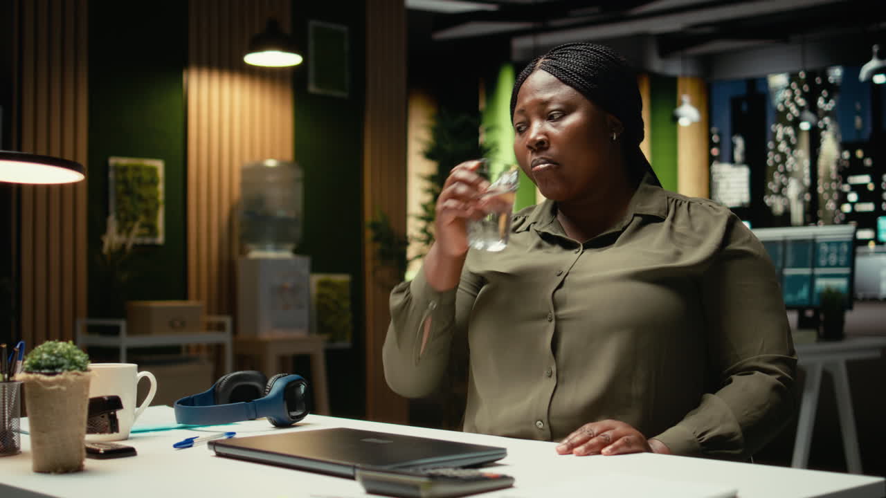 Mulher de negócios negra desligando sua estação de trabalho com luminária e computador
