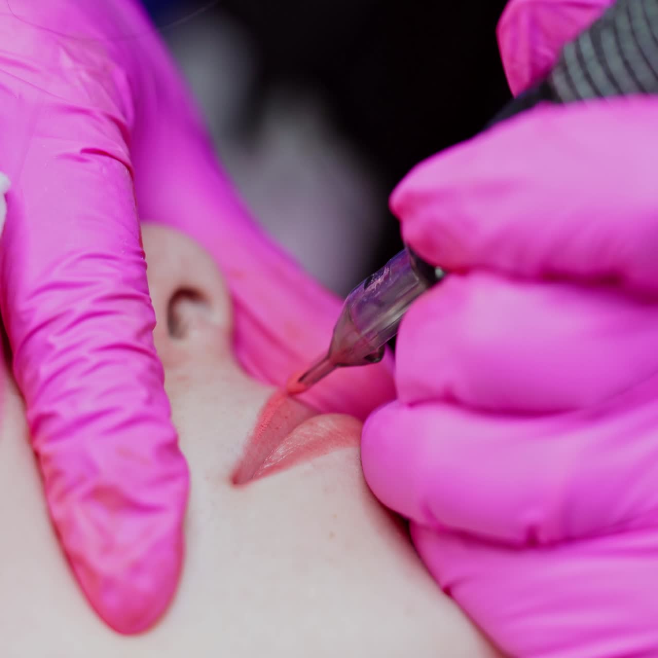 Procedure of lip tattooing. Skilled cosmetologist doing lips permanent make-up for female client. Beauty concept. Close-up.