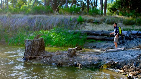 male hiker standing with arms up near a lake 4k