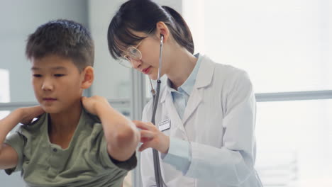 female doctor examining asian kid and showing thumb up