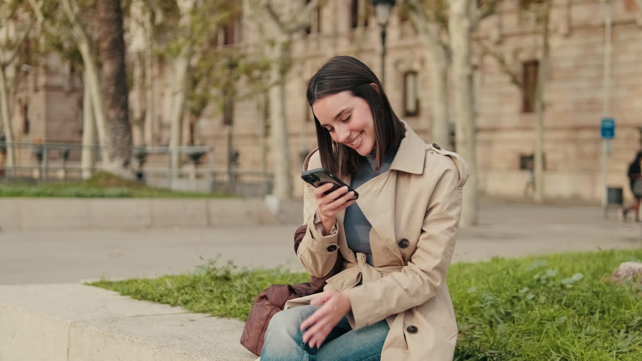 Smiling Young Woman Using Smartphone in City Park
