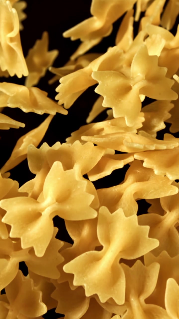 Farfalle secche che cadono al rallentatore su uno sfondo nero