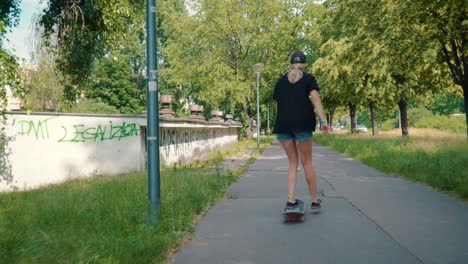 una chica monta una patineta en la calle en un parque de verano.