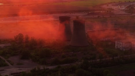 Industrial-smokestacks-surrounded-by-smoke-emissions-illuminated-by-the-orange-sunlight,-high-contrast-close-up-shot